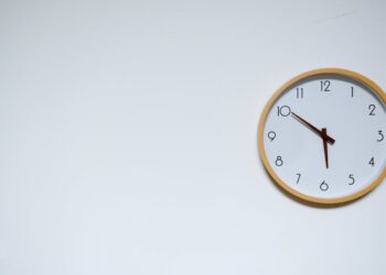 Simple wall clock with wooden frame against a white background, showing the time 10:10.